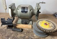 Front view of bench grinder with tool rests and extra wheels