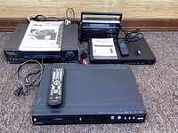 Group shot of all four electronics with remotes, manuals and cables visible