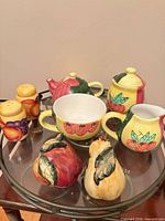 Full set displaying teapot, sugar bowl, creamer, shakers and decorative fruit pieces