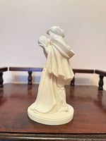 Full side view of ivory resin Romeo & Juliet figurine on wooden surface