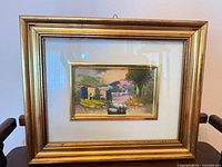 front view of framed landscape painting showing gold frame, white mat and artwork