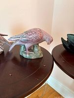 Close view of single bird figurine in feeding pose, pastel glazing