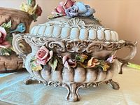 Tureen angled view showing lid, side handles, raised roses and ornate base