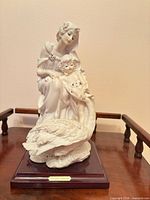 Full view of figurine on wood base showing figures and swan