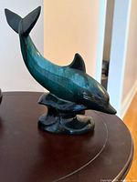 Green-blue glazed ceramic dolphin figurine standing on stylized waves