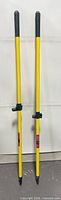 Full view of both yellow broom poles standing upright showing top and bottom fittings
