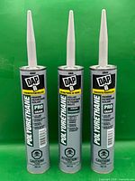 Front view of three DAP sealant tubes with nozzles attached