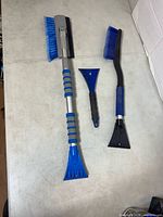 Three car snow-clearing tools laid out on table
