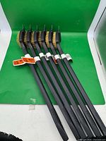 Six identical BBQ wire brushes lined up showing full length