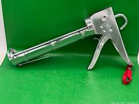 Full view of chrome steel ratchet caulking gun with red strap