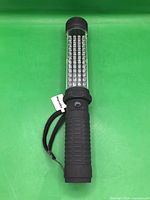 Flashlight standing upright showing side LED array and wrist strap