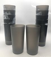 Stacked gray plastic tumblers, some still wrapped, showing quantity