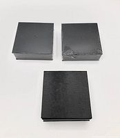 Three black textured boxes, two shrink-wrapped