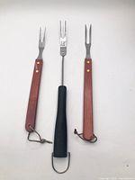 Three BBQ forks laid out showing handles and tines