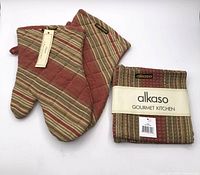 pair of oven mitts beside packaged dish cloths