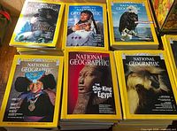 Stacks of National Geographic magazines showing various covers including Jane Goodall, She-King of Egypt, wildlife and cultural themes