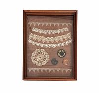 Full view of framed display showing doily, lace trims, buttons