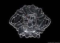Top view of clear pressed glass handled cake plate showing floral pattern and handles