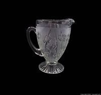 Full view of clear pressed glass pitcher showing handle, spout, pedestal base