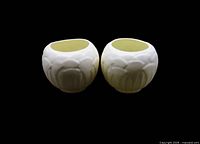 Front view of both ivory ceramic lotus candle holders showing overall form and color