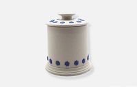 Cylindrical white stoneware jar with lid in place, blue leaf motif visible