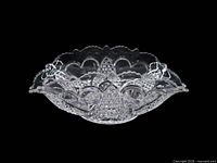 Side profile of pressed glass banana bowl showing heart and thumbprint pattern and scalloped rim