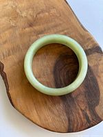 Top view of pale green jade bangle on wooden surface