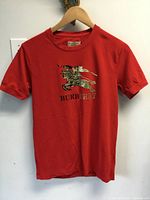 Front view of red Burberry T-shirt hanging