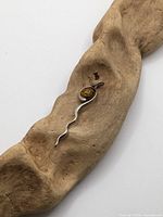 Front view of sterling silver amber scroll pendant on driftwood