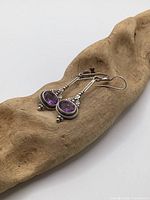 Earrings on driftwood showing front design with amethyst stones