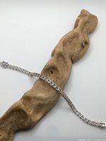 Full view of sterling silver CZ tennis bracelet draped on wooden prop