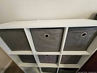 Front view of white 3x3 cube shelf showing gray bins inserted