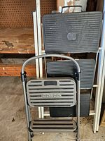 Cosco 2-step stool in front of folded 3-step ladder