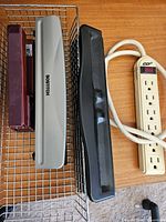 Stapler, two hole punches in wire tray, power strip