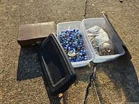 Overall view of two clear tubs with contents, brown case and black lid visible