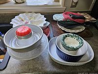 Overall lot showing tube pan on glass plate, nested baking dishes, platters, potholders stack