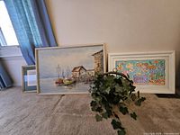 Three framed artworks: seascape, mermaid illustration, calligraphy print; ivy plant also present but not part of lot