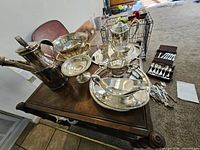 Group shot of silver-plated serveware pieces on table with flatware roll
