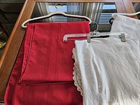 Red cloth and white lace-edged cloth on hangers