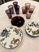 Stacked fruit motif plates, aubergine glass plates, tall and short purple glasses