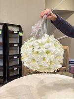 Hand holding one floral light showing wiring and ribbon hangers