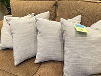 Four gray linen-style pillows on sofa