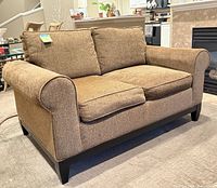 Front view of brown loveseat showing cushions, rolled arms, wood base and feet