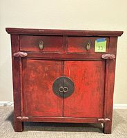 Front view of red distressed Asian style chest showing drawers, doors, hardware