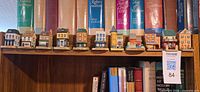 Row of miniature houses on shelf under reference books