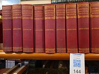 Spine view of seven of the fourteen matching red cloth volumes showing gilt titles