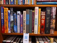Shelf showing 16 modern fiction books with visible titles and authors