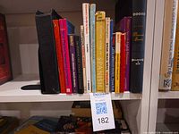 Row of Spanish language books on shelf with MaxSold tag 182 visible