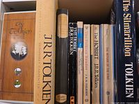 Shelf showing all nine spines: The Tolkien Family Album; J.R.R. Tolkien: A Biography; unidentified black spine title; The Hobbit; The Tolkien Reader; The Fellowship of the Ring; The Two Towers; The Return of the King; The Silmarillion