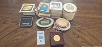 Multiple stacks of assorted drink coasters, wood coaster, medallion box, lot tag